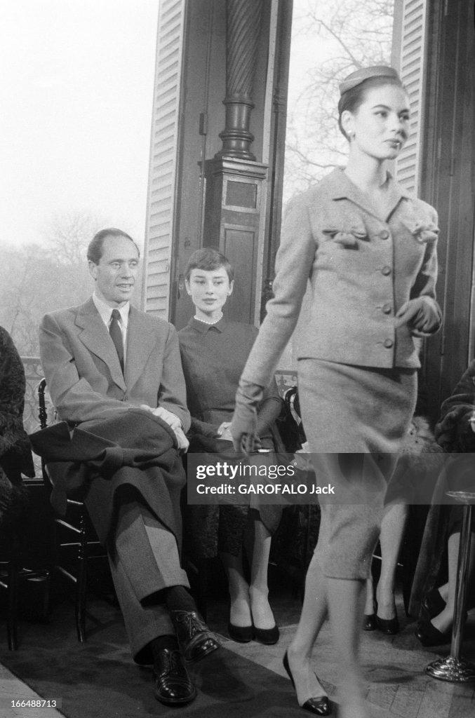 Audrey HEPBURN et Mel  FERRER en vacances. Le couple d'acteurs en visite chez le couturier Hubert Givenchy. En l'honneur d'Audrey le couturier a baptisé un modèle de robe Sabrina. Les deux acteurs sont assis côte à côte et regardent défiler une mannequin portant un tailleur.