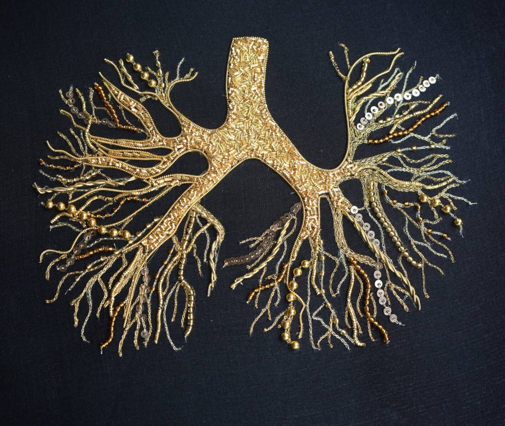 A photo of gold embroidered and beaded lungs on a black background
